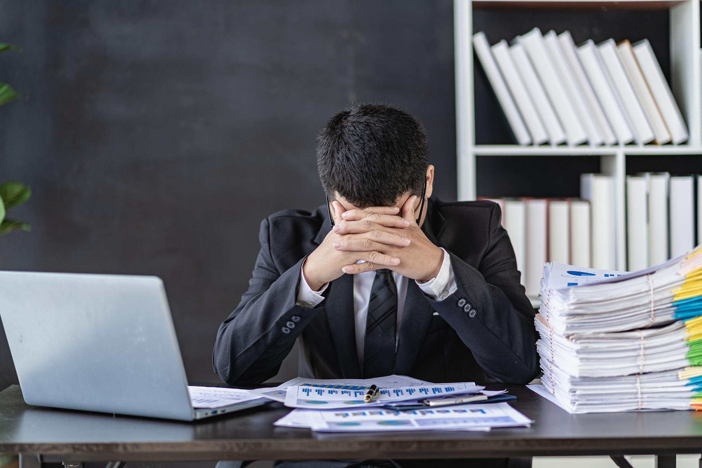 Tired businessman worried about financial problems senior executive sitting at desk in office examining company financial accounting documents feeling worried about taxes